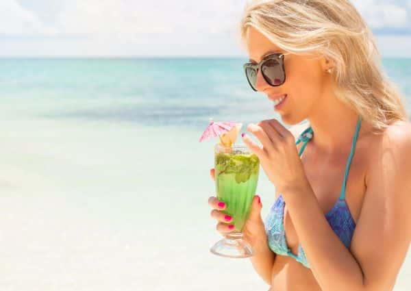 Garota tomando um drink na beira da praia