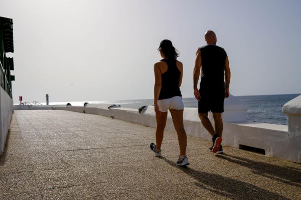 Homem e mulher fazendo caminhada à beira-mar após Lipo HD