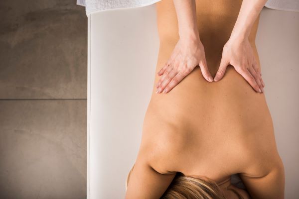 Mulher fazendo sessão de drenagem linfática nas costas para aliviar edemas e dores após lipoaspiração nas costas.